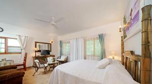 um quarto com uma cama branca, uma mesa e cadeiras em Beach House Condos, Negril em Negril