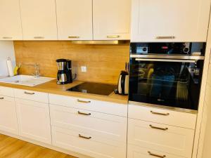 a kitchen with white cabinets and a black microwave at Ferien-Apartment Irisblüte - mit priv Strandzugang in Friedrichshafen