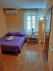 um quarto com uma cama roxa e uma janela em Apartment Surya em Rogoznica