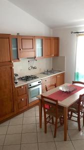 a kitchen with wooden cabinets and a table and a table and chairs at CAMY Apartment Scopri Tortolì Appartamento Centrale vicino alle Spiagge! in Tortolì