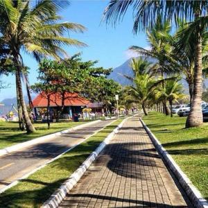 eine Straße mit Palmen und einem Berg im Hintergrund in der Unterkunft Colônia de Férias SITRAEMFA in Peruíbe