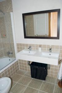 a bathroom with a sink and a toilet and a mirror at Residencial Massana in Alcalá de la Selva