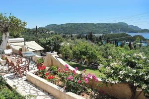 um jardim com mesa, cadeiras e flores em angela studios em Paleokastritsa