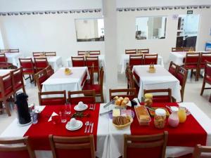 ein Esszimmer mit weißen Tischen und roten Tischdecken in der Unterkunft Colônia de Férias SITRAEMFA in Peruíbe