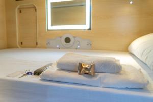 a white towel with a gold bow on a bed at HosteLit, Capsule Hostel in Santa Cruz de la Palma