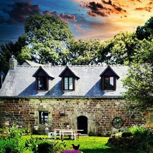 a stone house with a bench in a yard at Chestnut in Langoëlan