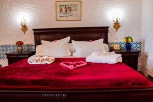 una camera da letto con un grande letto rosso con due asciugamani di ROSE M'GOUNA a El Kelaa des Mgouna