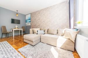 uma sala de estar com um sofá branco e uma mesa em Apartament wakacyjny na Przymorzu em Gdansk
