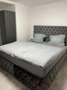 ein großes Bett mit einem gepolsterten Kopfteil in einem Schlafzimmer in der Unterkunft All In in Oberhausen