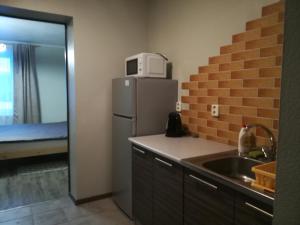 a kitchen with a refrigerator and a sink and a bed at Oāze Smiltenē in Smiltene