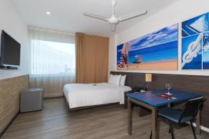 Habitación de hotel con cama, escritorio y TV. en Pop Art Hotel CLC Mamonal Cartagena, en Cartagena de Indias