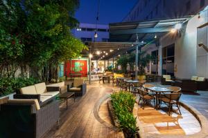 un patio al aire libre con mesas, sillas y árboles en Pop Art Hotel CLC Mamonal Cartagena, en Cartagena de Indias