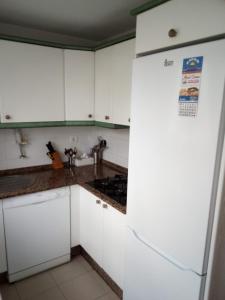 a kitchen with white cabinets and a refrigerator at Primera línea de playa casita adosada in Chiclana de la Frontera