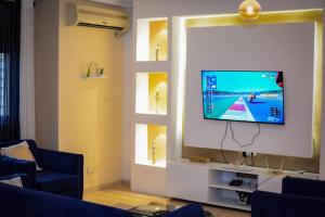 a living room with a tv on a wall with windows at Appartement Cosy 3 bonapriso in Douala