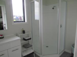 a white bathroom with a shower and a mirror at The Bunkhouse in Waiau