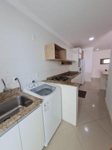 uma cozinha branca com um lavatório e uma máquina de lavar louça em Amplo e aconchegante apartamento com 3 quartos a 50m da praia de Bombas em Bombinhas