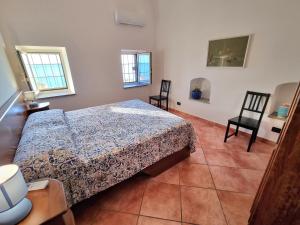 a bedroom with a bed and two chairs and two windows at Il Limoneto in Furore