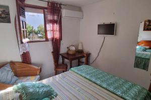 a bedroom with two beds and a tv on the wall at Villa en pleine nature située à 5min d'une plage in Le Gosier