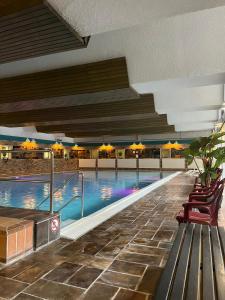 a swimming pool in a hotel with chairs and umbrellas at Berg-Blick-Fewo in Bad Harzburg