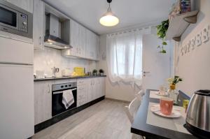 龍達的住宿－13 Avenida Andalucía，厨房配有白色橱柜、桌子和炉灶。