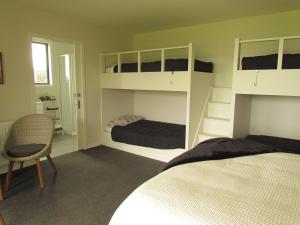 a bedroom with two bunk beds and a chair at The Bunkhouse in Waiau
