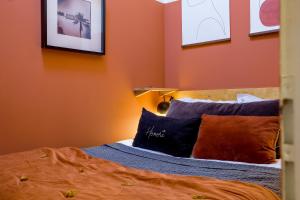 1 dormitorio con paredes de color naranja y 1 cama con almohadas en HONORÊ - Suite Terracotta en Lyon