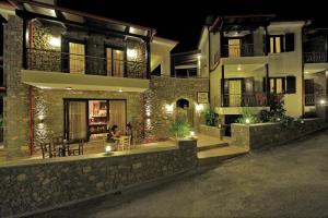 Dianthos Guesthouse في Kiriákion: مبنى في الليل مع أشخاص يجلسون خارجه