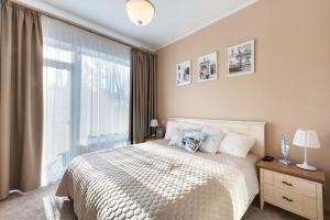 a bedroom with a bed and a large window at Turaidas Kvartals Four Seasons Luxury Apartment in Jūrmala