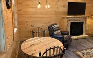 a living room with a table and a chair and a fireplace at Briarwood Cabin by Amish Country Lodging in Berlin