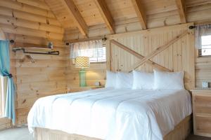 a bedroom with a white bed in a wooden wall at Hummingbird Haven Cabin by Amish Country Lodging in Berlin