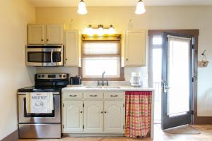 a kitchen with white cabinets and a sink and a stove at Village Dreams Cottage by Amish Country Lodging in Berlin