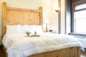 a bedroom with a large white bed with a wooden headboard at Village Dreams Cottage by Amish Country Lodging in Berlin