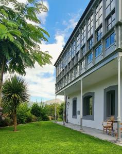 a building with a grass yard next to a building at Villa Marta Casa de Indianos Passive House in Villanueva de Ardisana