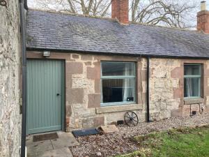 una casa in pietra con una porta verde e due finestre di Charleton Farm Cottages a Montrose