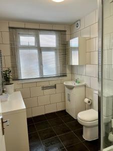 a bathroom with a toilet, sink and tub at Gladstone Park Guest House in London