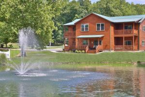 a log house with a pond in front of it at Waterview Lodge by Amish Country Lodging in Millersburg