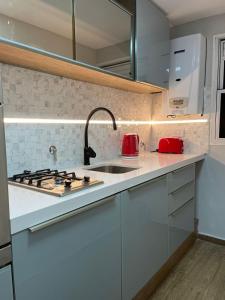 a white kitchen with a sink and a stove at Departamento Fabuloso in Rosario