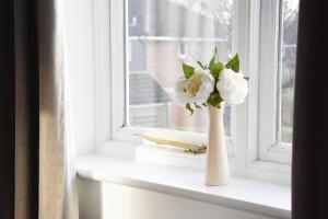 un jarrón de flores sentado en un alféizar de la ventana en Broadgate House, en Norwich 43 fotos más