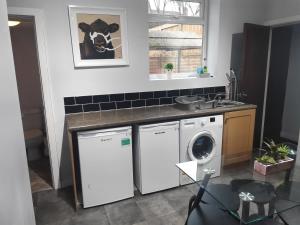 a kitchen with a washing machine and a sink at The Old Post Box in Leeds