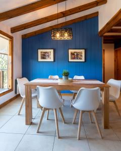 comedor con mesa de madera y sillas blancas en Oliver Mountain Home Blue en San Martín de los Andes