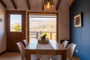 comedor con mesa, sillas y ventana en Oliver Mountain Home Blue en San Martín de los Andes