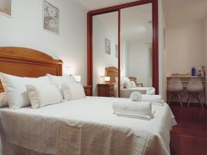 a bedroom with a large white bed with towels on it at Martínez Rooms Pilgrims in Caldas de Reis