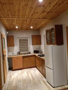 a kitchen with a white refrigerator and wooden cabinets at Zielona Ostoja in Ryn