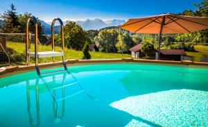 a swimming pool with a chair and an umbrella at Apartment Motzenhof - Stadtnähe Salzburg - modernes Bauernhoferlebnis inklusive in Adnet