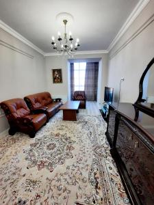 ein Wohnzimmer mit einer Ledercouch und einem Tisch in der Unterkunft Исы Байзакова 131, новостройка in Pawlodar