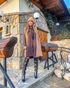 a woman standing on steps in a coat and boots at Witkówka New Folk Luxury - Sauna & SPA x in Kościelisko