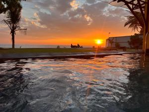 a sunset over a swimming pool with the ocean at Amanda Beach Villas in Unawatuna