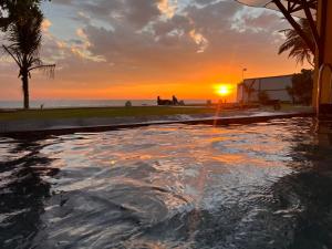 a swimming pool with the sunset in the background at Amanda Beach Villas in Unawatuna