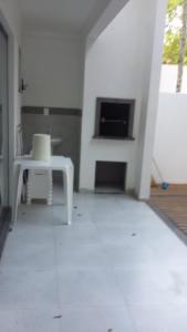a white room with a table and a fireplace at Casa geminada 2 no Mariscal in Bombinhas