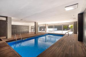 - une piscine d'eau bleue dans un bâtiment dans l'établissement FORUM BEACH 2 AND POOL APARTMENT BARCELONA, à Barcelone
